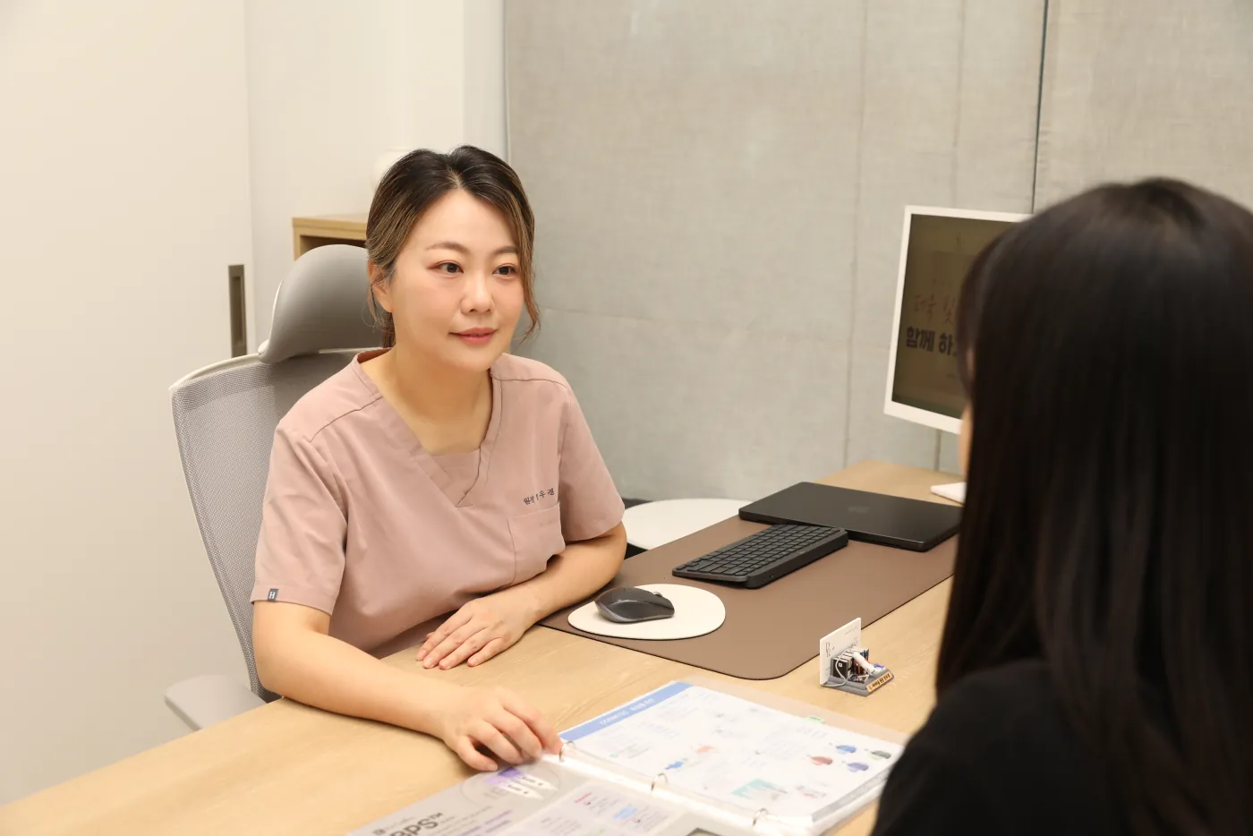 진료실 책상에서 자료를 짚으며 상담하는 안우경 대표원장